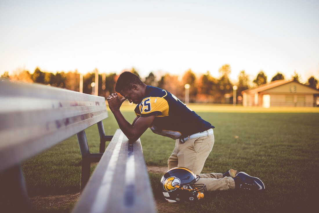 American footballer praying on the football field.