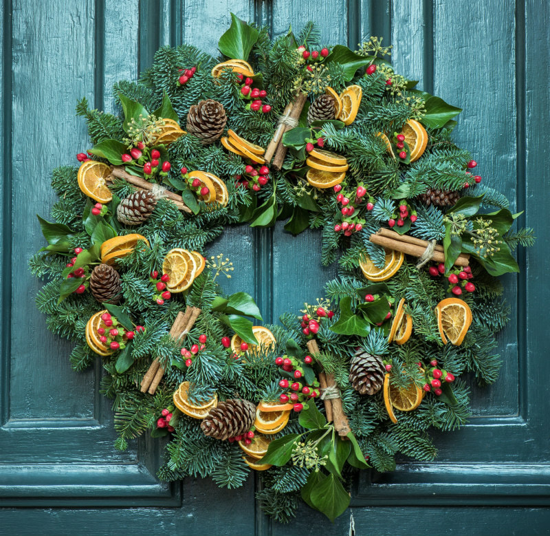 Wreath decorated with berries, cones, orange slices and cinnamon sticks.