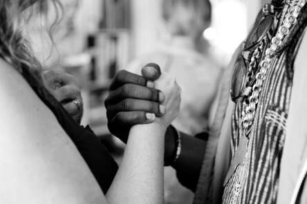 2 women from different ethnic groups, clasping hands, illustrating the community of believers is inclusive.
