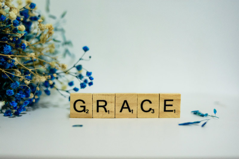 The word 'GRACE' in Scrabble letters, by a bunch of flowers.