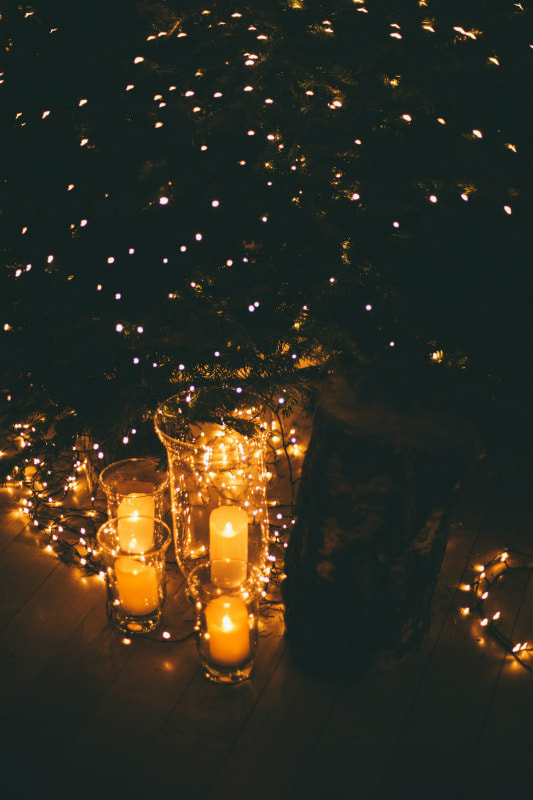 Candles glowing in the dark with background of white fairy lights.