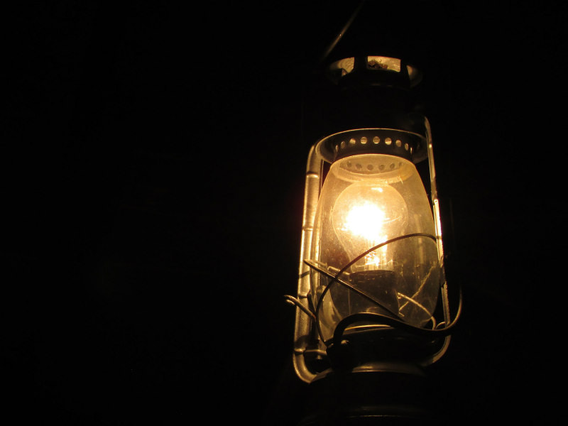 Lit hurricane lantern in the darkness.