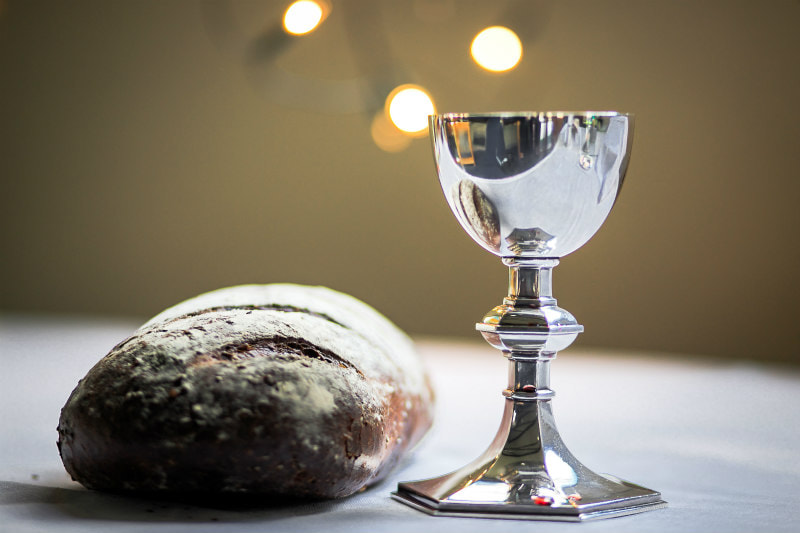Goblet and loaf of bread with crown of thorns.