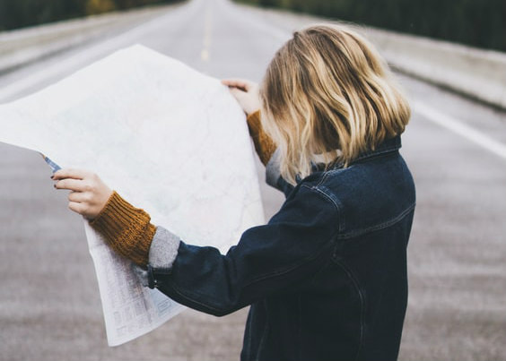 Close-up of woman examining a map, on an empty road, illustrating the ‘journey of faith’ site map.