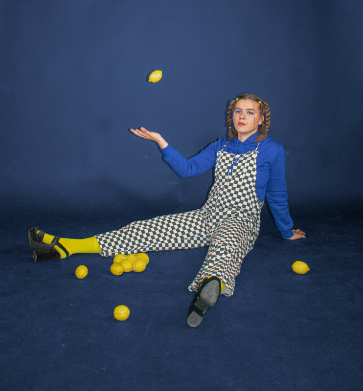 Juggler sitting on the floor with lemons around her