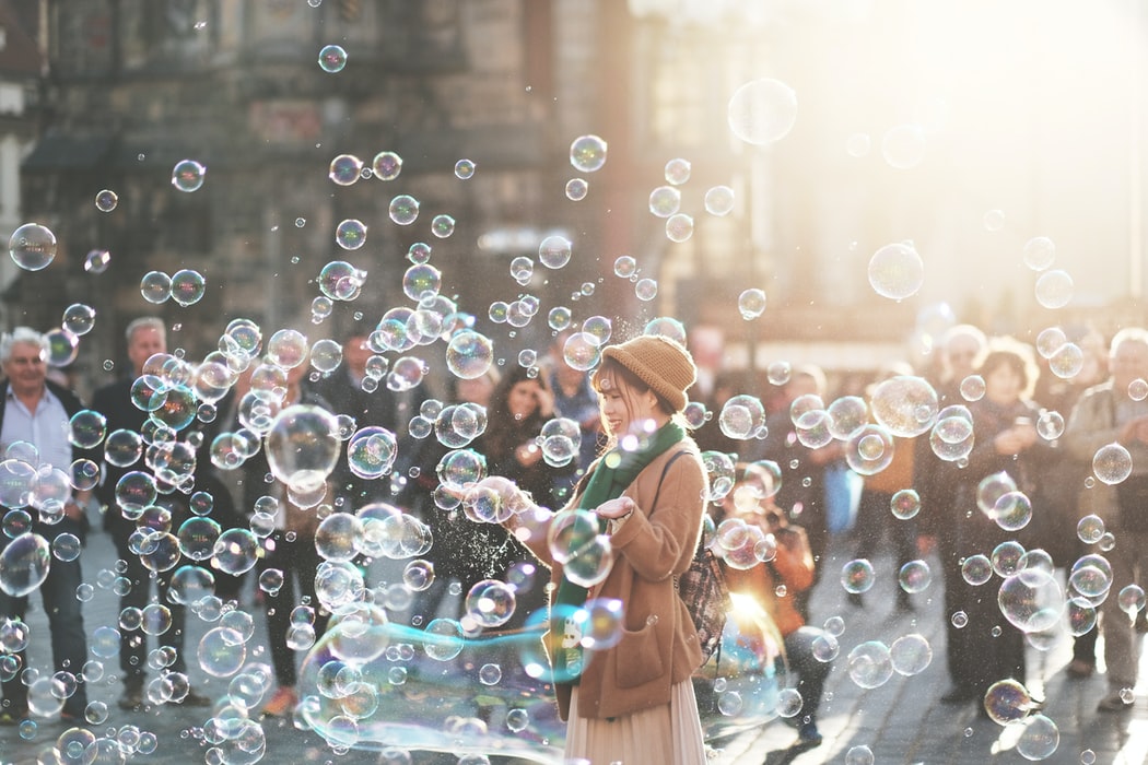 Girl in a city street, surrounded with bubbles, illustrating the idea that play for adults, can be Holy Spirit-inspired.