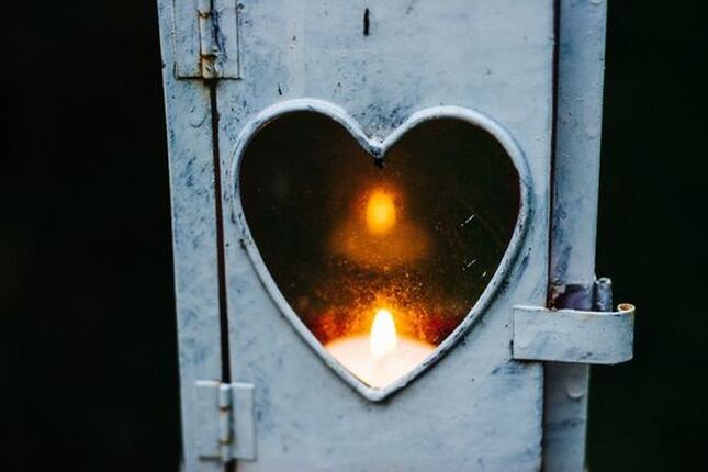 Candle in tin lantern, glowing through a heart-shaped 'window'.
