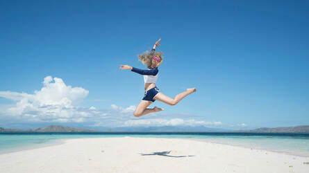 Girl leaping for joy on an empty beach, illustrating that each one has a unique way of celebrating God’s interventions.
