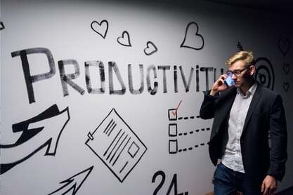 Man on phone, with productivity whiteboard behind, illustrating the idea of perfection in the workplace.