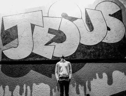 Graffiti-painted word: 'Jesus', illustrating section 'in the name of the Lord'.