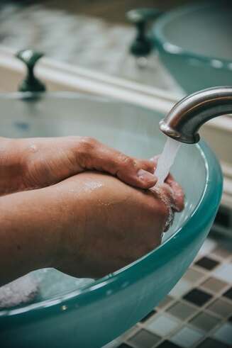Hand-washing in a basin, illustrating ‘Baptism: meaning and purpose’.