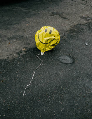 Punctured smile-face balloon, illustrating blog theme, 'Overcoming disappointment'.