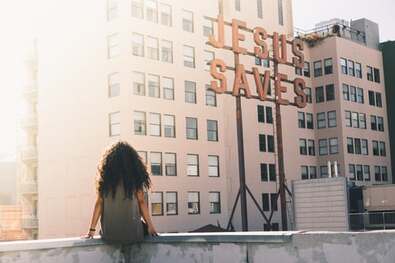 Girl on a roof gazing at an inaccessible ‘Jesus saves’ sign, illustrating the difficulties some find with personal devotions.