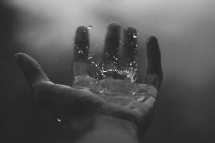 Close-up of water splashing onto the palm of a hand, illustrating the idea that Sabbath rest is about worship.