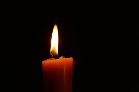 Close-up of a candle flame in the darkness, illustrating the idea that ‘sharing bread’ brings us into God’s presence.