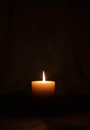 Single lit candle in the darkness.