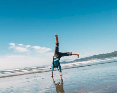 Person doing cartwheels on a sunny beach, illustrating the page title, ‘Spirit-led Recreation: The Rhythm of Play’.