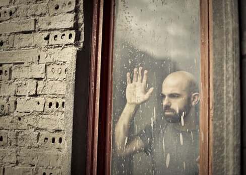 Man looking hopelessly through a window, illustrating the page theme, ‘tired of struggling’.