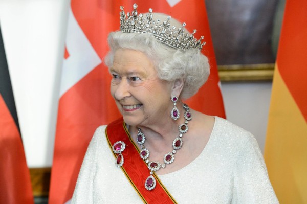 Queen Elizabeth smiling, wearing crown and royal sash.