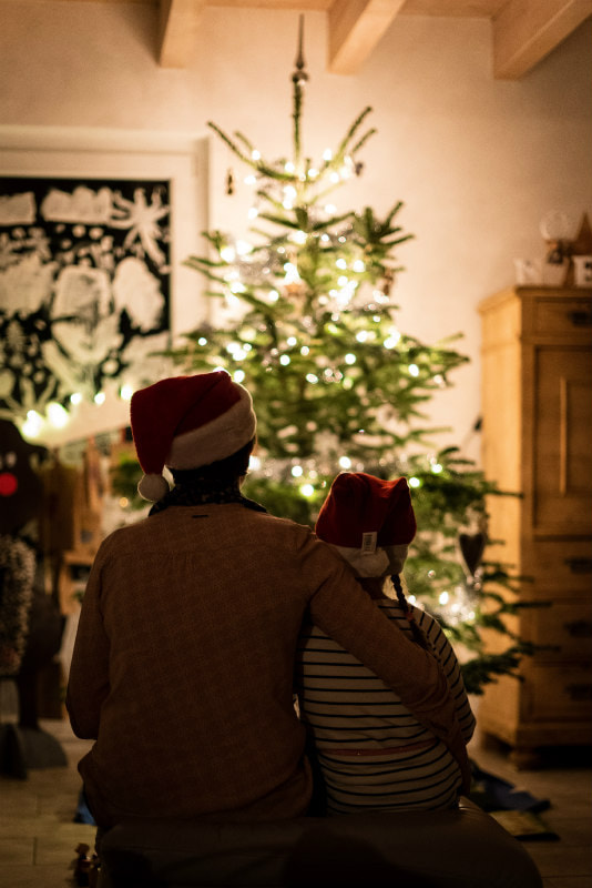 Woman and child gazing at a lit Christmas tree.