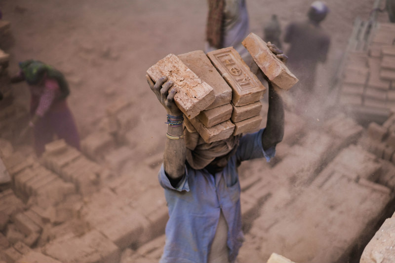 Man carrying a load of bricks on his head.