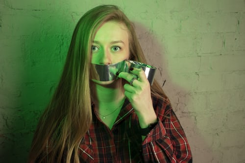 Girl with duct tape over her mouth, illustrating the section on ‘The Problem with negative Words’.