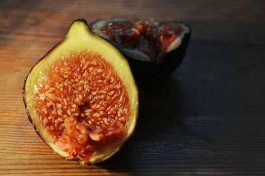 A fig, halved on a wooden table.